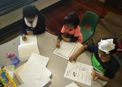 Children engaged in writing activities at a table with papers and notebooks.
