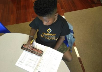 A young boy doing homework with a pencil and calculator.
